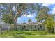 Charming single-story home featuring a manicured lawn, mature shade trees, and a secure black metal fence at 1827 Oregon Ne Ave, St Petersburg, FL 33703