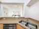 Open kitchen sink and stainless steel dishwasher beneath counter, with bar overlooking the living area at 200 4Th S Ave # 229, St Petersburg, FL 33701
