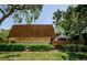 Rear exterior view of a brick home featuring a tile roof and lush greenery at 2706 11Th Ct, Palm Harbor, FL 34684