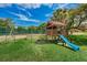 A community playground features a swing set, a playhouse with a blue slide, and a backdrop of a tennis court at 2706 11Th Ct, Palm Harbor, FL 34684