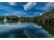 Beautiful community pond with fountain, trees, and blue skies with light clouds reflected in the water at 2706 11Th Ct, Palm Harbor, FL 34684
