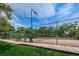 Community tennis court surrounded by a tall fence, a wooden walkway and a grassy area, creating a scenic recreational space at 2706 11Th Ct, Palm Harbor, FL 34684