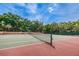 A community tennis court with a net in place, surrounded by lush trees and manicured landscaping at 2706 11Th Ct, Palm Harbor, FL 34684
