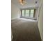 Carpeted bedroom featuring neutral carpet, ceiling fan, and three windows with wooded views at 27653 Pleasure Ride Loop, Wesley Chapel, FL 33544