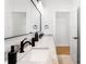 Bathroom featuring double sinks with marble countertops and modern black fixtures, a large mirror, and bright lighting at 3002 W Abdella St, Tampa, FL 33607