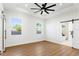 Spacious bedroom with wood floors, a ceiling fan, neutral walls, two bright windows, and sliding barn doors at 3002 W Abdella St, Tampa, FL 33607