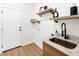 Well-organized laundry room featuring floating shelves, modern sink, and convenient access to outside at 3002 W Abdella St, Tampa, FL 33607