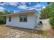 Exterior view of home with white siding, dark trim on the windows, and small seating area at 3008 E 38Th Ave, Tampa, FL 33610