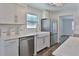 Well-lit kitchen featuring white cabinets, a stainless steel dishwasher, and hardwood floors at 3008 E 38Th Ave, Tampa, FL 33610