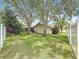 Spacious backyard featuring mature trees, green lawn, and a screened-in pool visible in the background at 3093 Hillside Ln, Safety Harbor, FL 34695