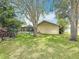 Lush backyard featuring mature trees, green grass, screened-in pool, and exterior of the home at 3093 Hillside Ln, Safety Harbor, FL 34695