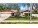 Charming single-story home features a well-manicured front yard with lush landscaping and a two-car garage at 3093 Hillside Ln, Safety Harbor, FL 34695