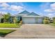 Charming single-story home with a well-manicured lawn, mature trees, and a three-car garage at 378 Wood Chuck Ave, Tarpon Springs, FL 34689