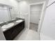 Bathroom with double vanity, dark wood cabinets, tile floors, and walk-in closet at 3810 Romano Busciglio St, Tampa, FL 33619