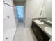 Bright bathroom featuring a double vanity with dark cabinets, and a tiled shower at 3810 Romano Busciglio St, Tampa, FL 33619