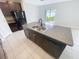 Kitchen island with stainless steel sink, dishwasher, and dark cabinetry at 3810 Romano Busciglio St, Tampa, FL 33619