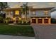 Elegant two-story residence illuminated at dusk, boasting a manicured lawn, stone accents, arched windows, and a spacious three-car garage at 4313 W Beachway Dr, Tampa, FL 33609