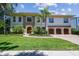 Stately two-story home with manicured lawn and lush landscaping, featuring a stone facade, arched windows, and a three-car garage at 4313 W Beachway Dr, Tampa, FL 33609