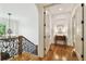 Elegant hallway featuring hardwood floors, white walls, iron stair rail, and stylish lighting fixtures at 4313 W Beachway Dr, Tampa, FL 33609
