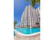 View of a high-rise condo building next to a beachside pool featuring lush tropical landscaping and an ocean view at 4950 Gulf Blvd # 409, St Pete Beach, Fl, FL 33706