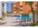 Inviting swimming pool next to condo building with tropical landscaping and poolside seating at 4950 Gulf Blvd # 409, St Pete Beach, Fl, FL 33706