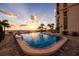 Outdoor pool near beach with ocean view at sunset, framed by palm trees and the condominium building at 4950 Gulf Blvd # 409, St Pete Beach, Fl, FL 33706