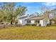 A view of the backyard features well-maintained landscaping and a charming white house with black window trim at 5526 Southernview Dr, Zephyrhills, FL 33541