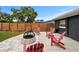 Backyard featuring stone pavers, a fire pit, red Adirondack chairs, lawn, and new wooden fence at 601 Patricia Ave, Dunedin, FL 34698