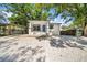 Bungalow with blue door, set on a gravel yard beneath mature trees at 8504 N 17Th St, Tampa, FL 33604
