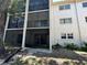 Exterior view of the condominium building featuring screened balconies, windows, and mature plantings at 861 Maple Ct # 104, Dunedin, FL 34698