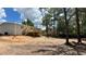 Exterior shot of a newly constructed home showcasing a spacious backyard with a wooden deck and fire pit area at 10040 Lake Dr, Weeki Wachee, FL 34613