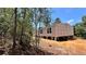 Side view of a neutral-colored single-story home with white-framed windows, elevated on concrete supports in a wooded area at 10040 Lake Dr, Weeki Wachee, FL 34613