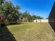 A spacious backyard featuring a partial privacy fence, green lawn, and mature trees at 10560 Lake Seminole Ter, Seminole, FL 33772