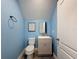 A compact half-bath with soft blue walls and wood look flooring, featuring a modern toilet and sink at 10560 Lake Seminole Ter, Seminole, FL 33772