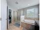 Bathroom featuring soaking tub, glass-enclosed shower, tiled flooring, and neutral paint at 10560 Lake Seminole Ter, Seminole, FL 33772
