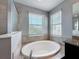 A well lit bathroom showcasing a luxurious soaking tub nestled between two windows at 10560 Lake Seminole Ter, Seminole, FL 33772