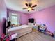 Bedroom boasts purple walls, a ceiling fan, and a window with natural light at 10560 Lake Seminole Ter, Seminole, FL 33772
