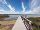 Picturesque view of a wooden dock extending into the tranquil water under a partly cloudy sky at 10560 Lake Seminole Ter, Seminole, FL 33772