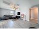 Living room featuring gray wood-look floors, a gray sofa, and a ceiling fan at 10560 Lake Seminole Ter, Seminole, FL 33772