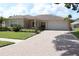 Beautiful home with a brick-paved driveway, lush landscaping, and an attached two-car garage at 11014 Peking Pl, Tampa, FL 33624