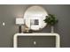Staged foyer featuring console table with stylish lamp, plant and round mirror reflecting art at 11817 Blue Diamond Trl, Parrish, FL 34219