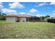 Exterior of the house featuring a screen enclosed lanai and a large, grassy backyard at 12012 Cromwell Way, Spring Hill, FL 34609