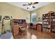 Bright bedroom featuring office space, hardwood floors and a ceiling fan at 12012 Cromwell Way, Spring Hill, FL 34609