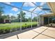 View of the screened-in lanai featuring concrete flooring and a glimpse of the lush backyard at 12012 Cromwell Way, Spring Hill, FL 34609