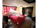 Bedroom with a red bed, window with red curtains, and outdated furnishings at 12049 132Nd Ave, Seminole, FL 33778
