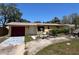 Charming single-story home with mature trees, a red garage door, and a well-lit entrance at 12049 132Nd Ave, Seminole, FL 33778