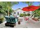 Lush backyard featuring an outdoor seating area, a vibrant red umbrella, and tropical landscaping at 1210 Bay Palm Blvd, Indian Rocks Beach, FL 33785