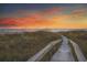 Stunning sunset over the beach with a wooden boardwalk leading to the sandy shore at 1210 Bay Palm Blvd, Indian Rocks Beach, FL 33785
