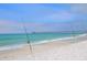 Scenic view of a sandy beach with fishing poles and a distant pier under a clear sky at 1210 Bay Palm Blvd, Indian Rocks Beach, FL 33785