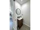 Charming powder room with wood cabinet vanity, round mirror, and modern fixtures at 12334 Country White Cir, Tampa, FL 33635